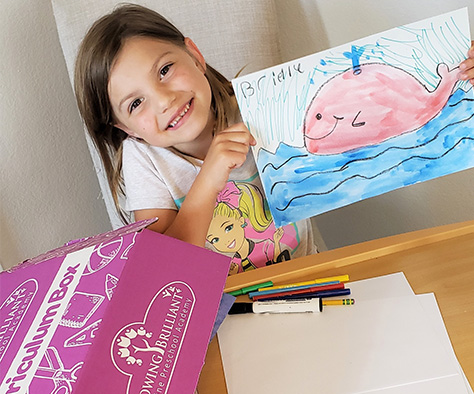girl holding up painting from online preschool